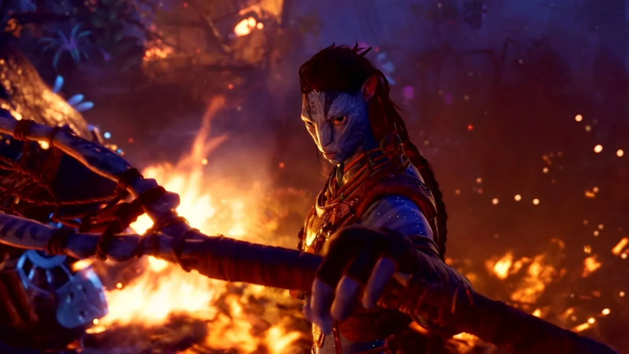 A fierce Na'vi warrior gripping a bow, poised in a dramatic stance amidst a fiery backdrop at night. The intense glow of flames reflects on the character's determined expression and traditional attire. The image portrays the warrior spirit and resilience of the Na'vi people in times of conflict.